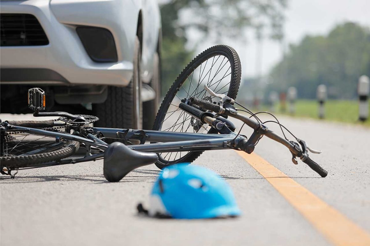 Bicycle and blue helmet on the ground after a car collision.